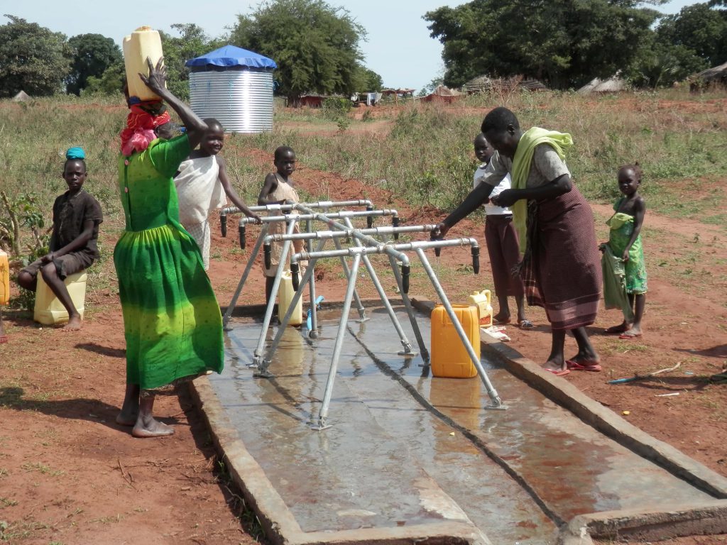 Frauen und Kinder bei einer Wasserentnahmestelle in Uganda.