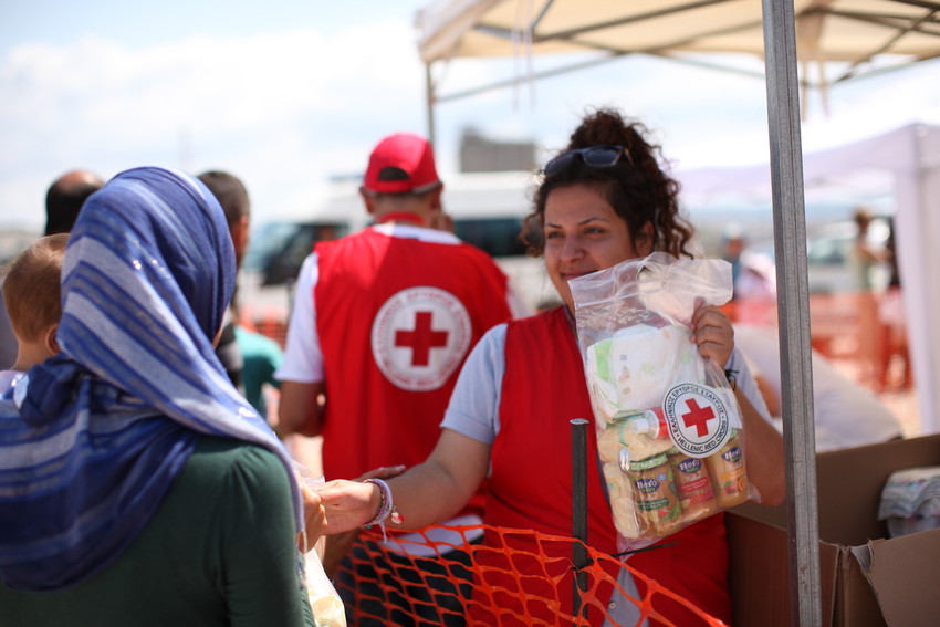 Rotkreuz Helferin übergibt ein Nothilfepaket im Flüchtlingscamp in Griechenland