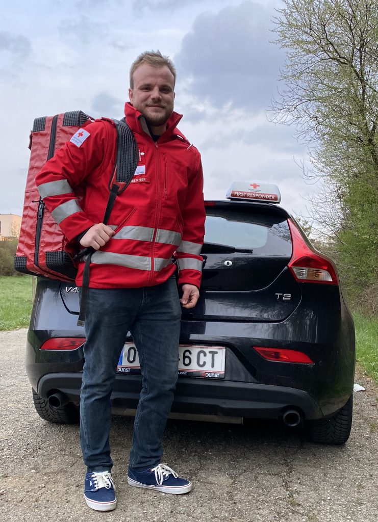 First Responder Brenner mit seinem Rucksack vor einem Auto