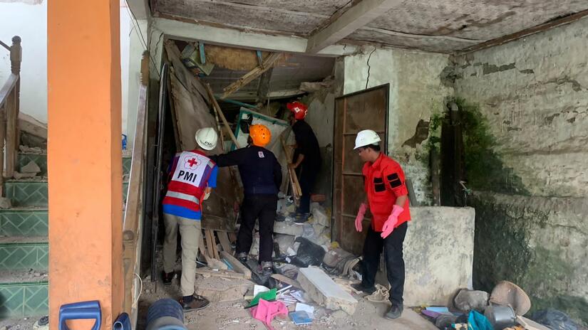 Mitarbeiter des Roten Kreuzes Indonesien helfen Überlebenden in Sicherheit zugelangen.
